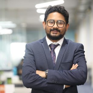 Confident man in a suit standing in a modern office, showcasing professionalism.
