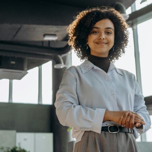 A confident businesswoman smiling in a modern office environment, exuding professionalism and warmth.